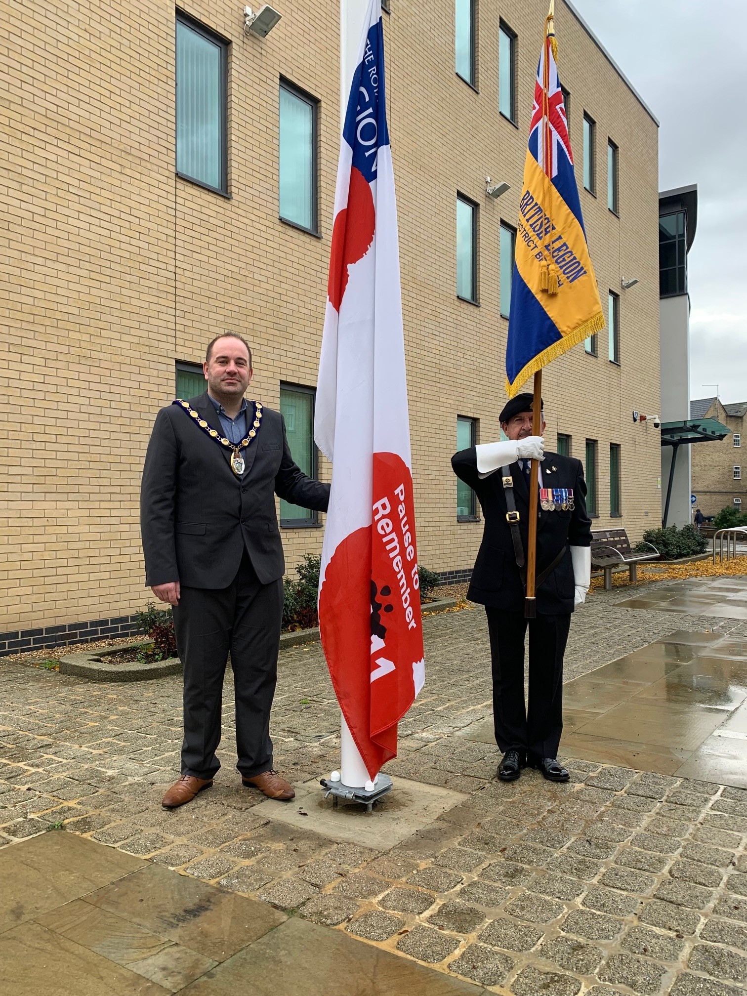 Picture of Chair, Cllr Michael Burke, raising the flag with RBL Standard Bearer, Nick Lynskey, Vice-Chairman of The Royal British Legion Huntingdon & District Branch.